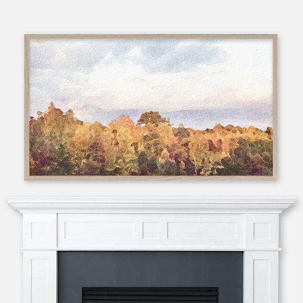 Watercolor painting of a tree line with colorful autumn foliage and cloudy sky displayed in Samsung Frame TV above fireplace