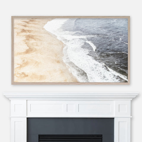 Neutral beige and gray beach aerial view watercolor landscape painting displayed in Samsung Frame TV above fireplace
