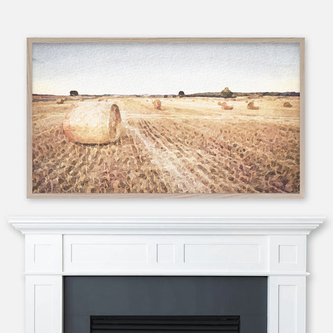 Country farmhouse watercolor landscape painting of hay bales in field displayed in Samsung Frame TV above fireplace
