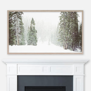 Watercolor winter landscape painting of foggy evergreen trees in the snow displayed in Samsung Frame TV above fireplace