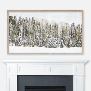 Watercolor winter landscape painting of a snow-covered pine tree forest displayed in Samsung Frame TV above fireplace